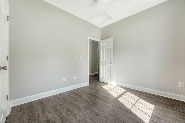empty room with dark wood-style floors, baseboards, and attic access