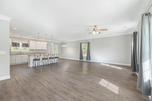 unfurnished living room with ceiling fan, plenty of natural light, and baseboards