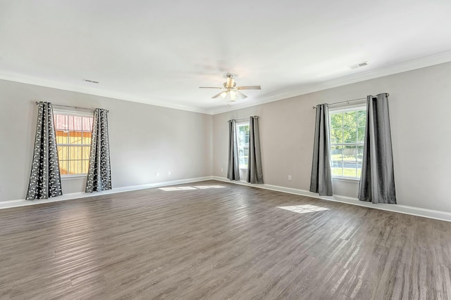 empty room featuring wood finished floors, ornamental molding, a ceiling fan, and visible vents