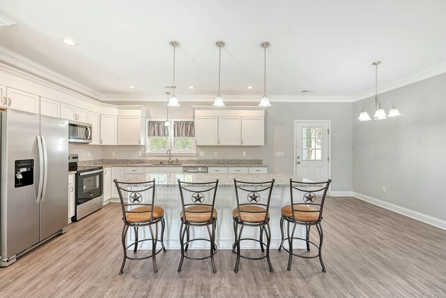 kitchen featuring stainless steel appliances, a center island, white cabinets, and a kitchen bar