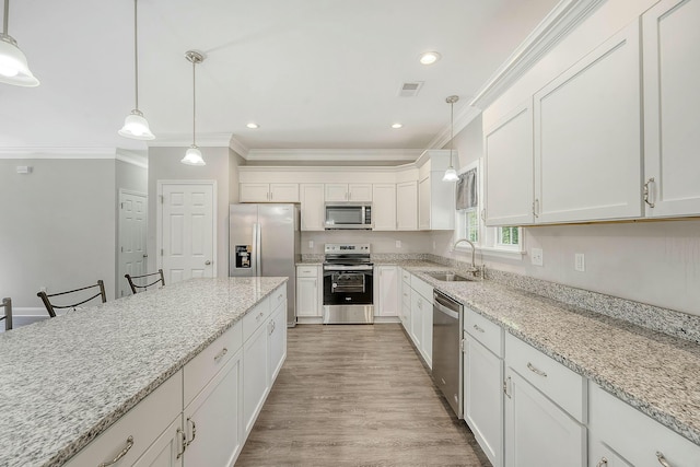 kitchen with crown molding, white cabinets, visible vents, appliances with stainless steel finishes, and a sink