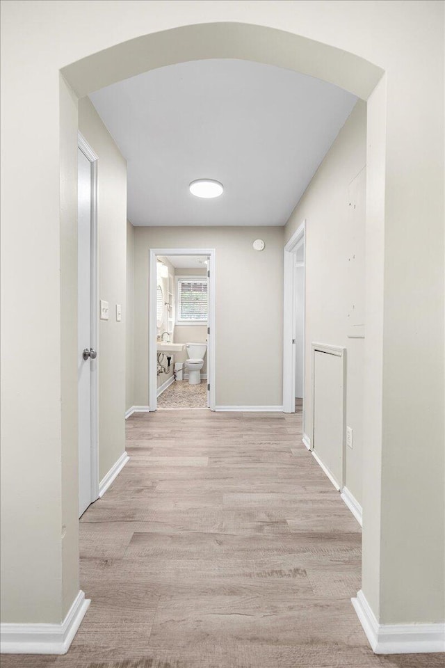 corridor with baseboards and wood finished floors