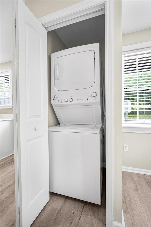 laundry room with estacked washer and dryer and wood finished floors