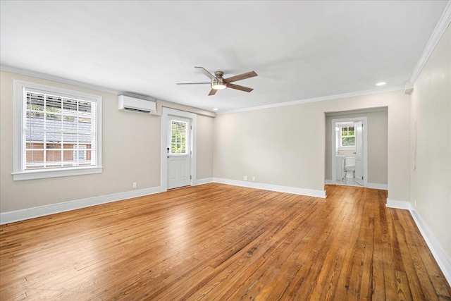 empty room with an AC wall unit, ceiling fan, light wood-type flooring, healthy amount of natural light, and ornamental molding