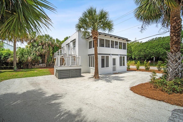 rear view of property with driveway, stairway, and stucco siding