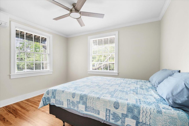 bedroom with multiple windows, wood finished floors, baseboards, ornamental molding, and a ceiling fan