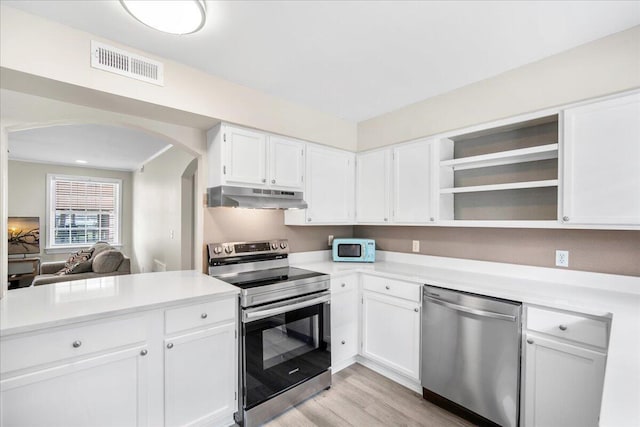 kitchen featuring stainless steel appliances, under cabinet range hood, arched walkways, light countertops, and light wood-style floors