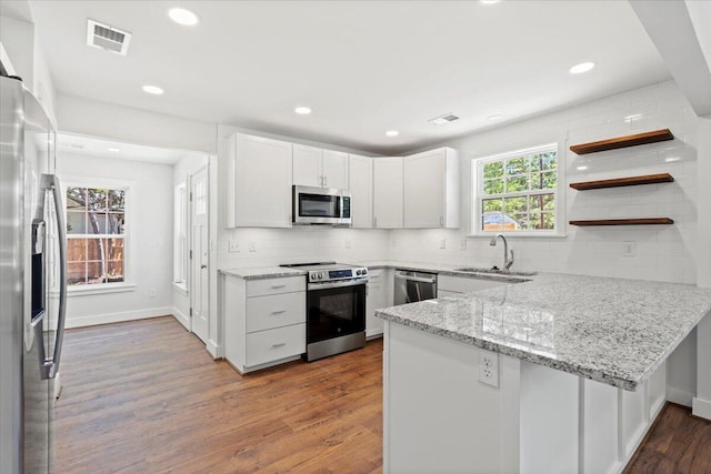 1430 E Montague Ave, North Charleston, SC 29405 - kitchen featuring stainless steel appliances, a sink, a peninsula, wood finished floors, and tasteful backsplash