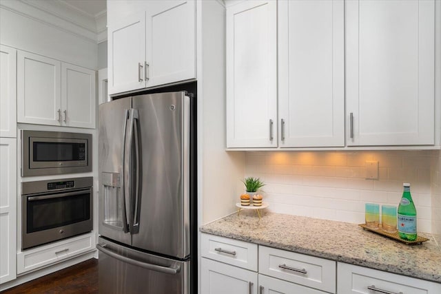 kitchen featuring light stone counters, crown molding, tasteful backsplash, appliances with stainless steel finishes, and white cabinetry