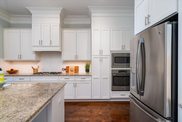 kitchen featuring tasteful backsplash, white cabinets, ornamental molding, light stone countertops, and stainless steel appliances