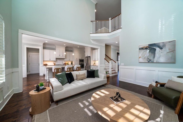 living area featuring ornamental molding, stairway, dark wood finished floors, and a decorative wall