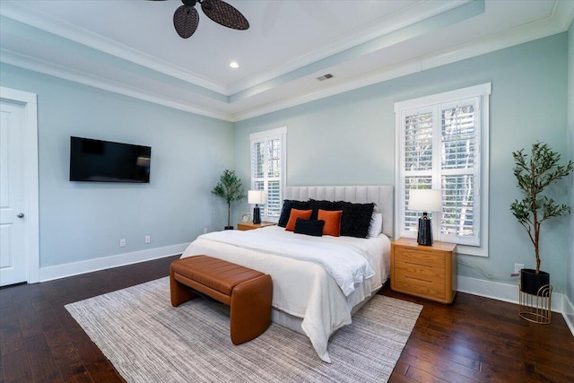 bedroom with dark wood finished floors, visible vents, baseboards, a raised ceiling, and crown molding