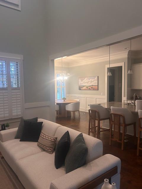 living room featuring ornamental molding, a decorative wall, and dark wood-style floors