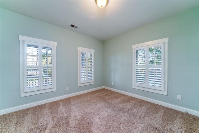 unfurnished room with a wealth of natural light, visible vents, and baseboards