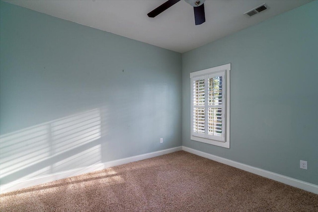 unfurnished room with carpet floors, a ceiling fan, visible vents, and baseboards