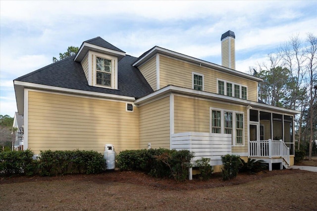 rear view of property featuring a sunroom and roof with shingles