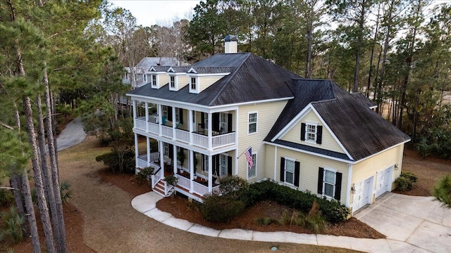 exterior space with a chimney, a porch, concrete driveway, a balcony, and a garage