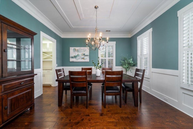 dining space with dark wood finished floors, wainscoting, ornamental molding, a decorative wall, and a notable chandelier