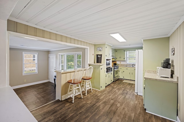 kitchen featuring appliances with stainless steel finishes, a peninsula, ornamental molding, green cabinetry, and dark wood-type flooring