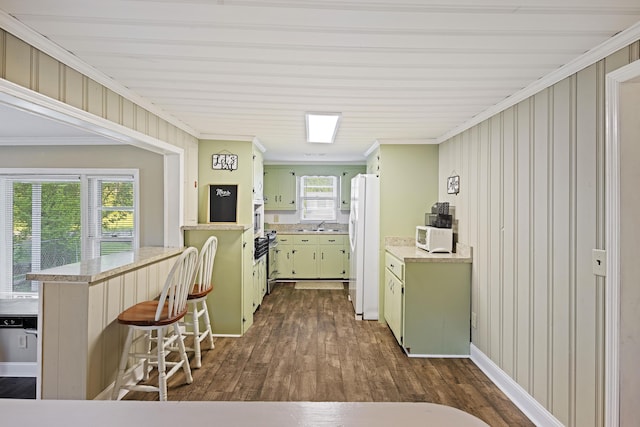 kitchen with white appliances, green cabinetry, dark wood-type flooring, light countertops, and a peninsula