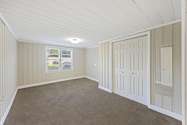 unfurnished bedroom featuring dark colored carpet, a closet, and crown molding