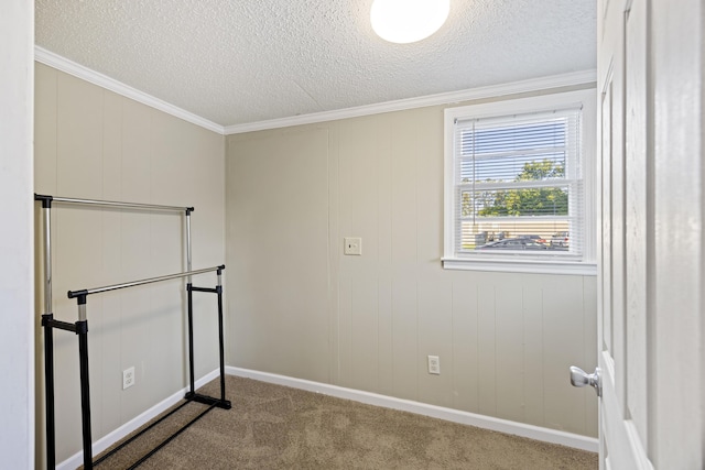 carpeted empty room with a textured ceiling, crown molding, and baseboards