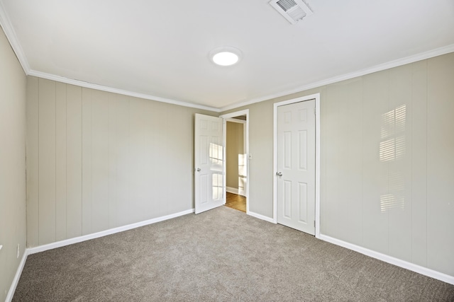 unfurnished bedroom featuring carpet flooring, ornamental molding, and baseboards