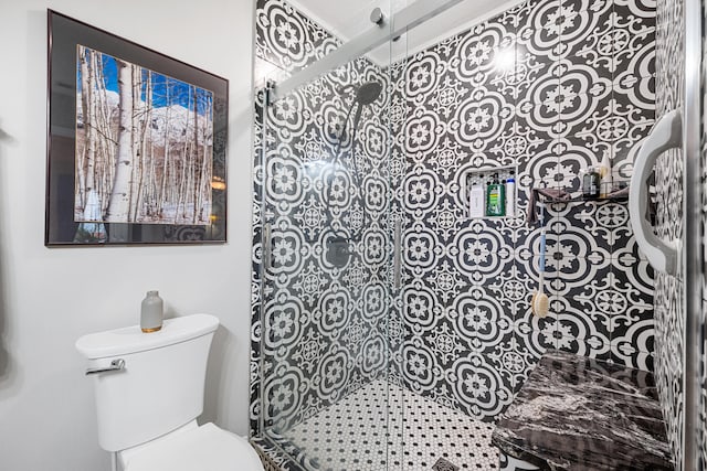 bathroom featuring toilet and a shower with shower door