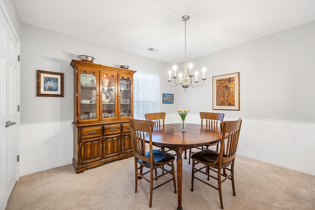 dining room featuring a textured ceiling, light carpet, and a chandelier