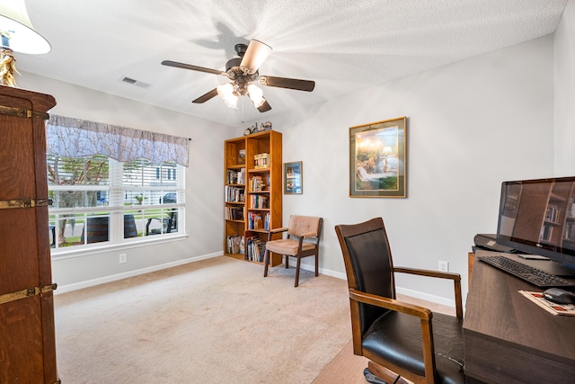 carpeted office featuring ceiling fan and a textured ceiling