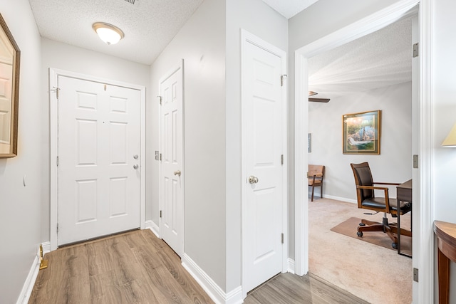 hallway featuring a textured ceiling and light hardwood / wood-style flooring