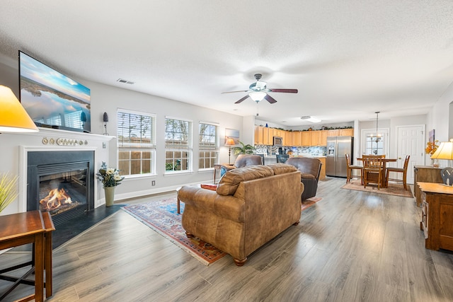 living room with ceiling fan, wood-type flooring, and a textured ceiling