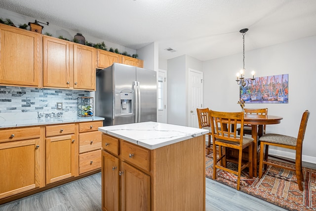 kitchen featuring a center island, a notable chandelier, stainless steel fridge, and light wood-type flooring