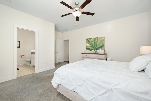 bedroom featuring ensuite bathroom, light colored carpet, and ceiling fan