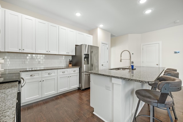 kitchen featuring stainless steel refrigerator with ice dispenser, sink, white cabinets, and a center island with sink