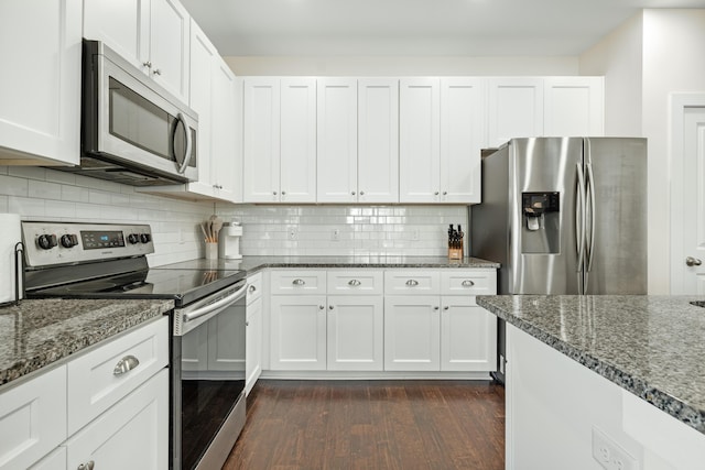 kitchen featuring appliances with stainless steel finishes, decorative backsplash, white cabinets, and dark stone counters