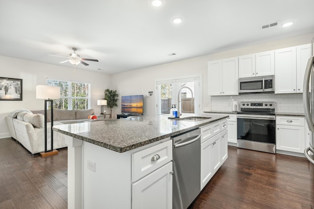 kitchen with appliances with stainless steel finishes, an island with sink, white cabinetry, and sink