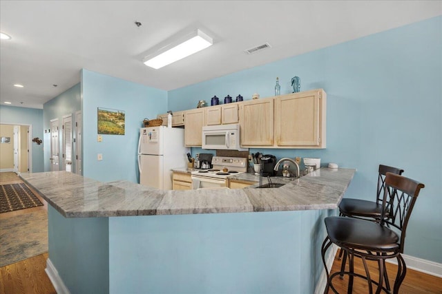 216 W Arctic Ave Unit 9, Folly Beach, SC 29439 - kitchen with white appliances, light brown cabinetry, dark wood-type flooring, a peninsula, and baseboards