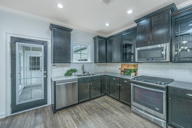 kitchen with dark wood finished floors, crown molding, appliances with stainless steel finishes, and a sink