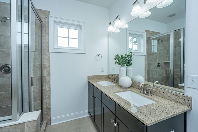 full bathroom featuring double vanity, a shower stall, baseboards, and a sink