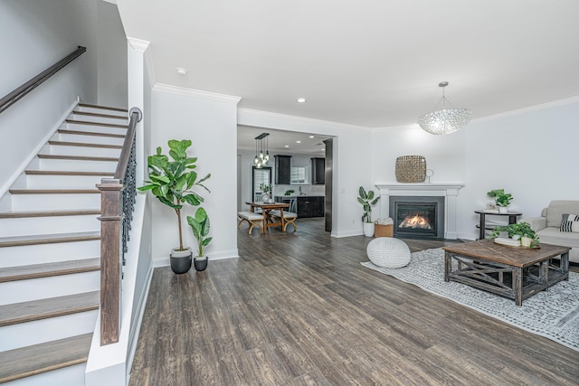 living room featuring a fireplace with flush hearth, ornamental molding, wood finished floors, baseboards, and stairs