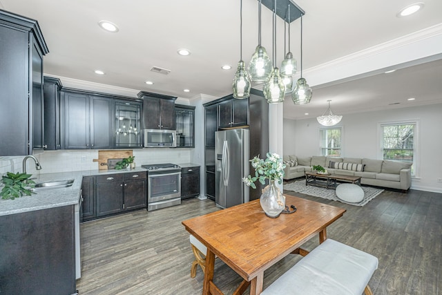 kitchen featuring wood finished floors, backsplash, stainless steel appliances, and a sink