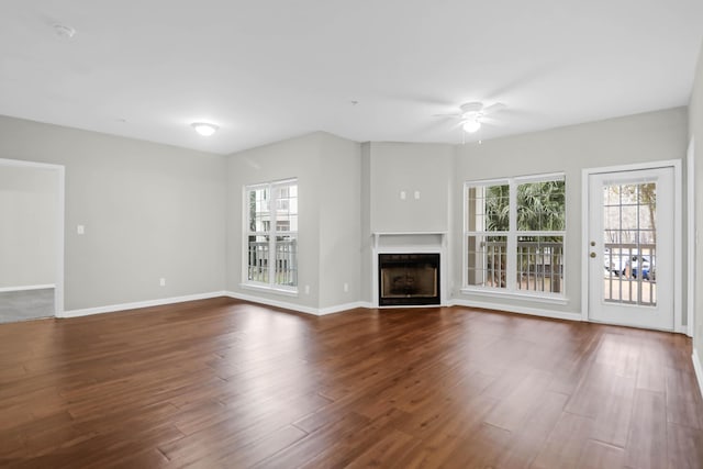 unfurnished living room with ceiling fan, a healthy amount of sunlight, and dark hardwood / wood-style floors