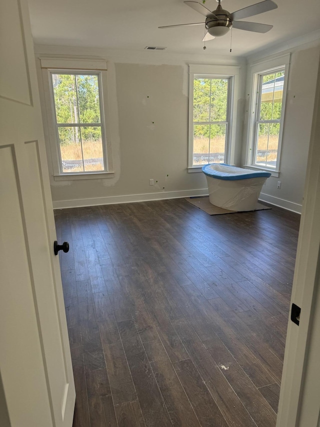 unfurnished room featuring dark wood-type flooring, visible vents, and baseboards