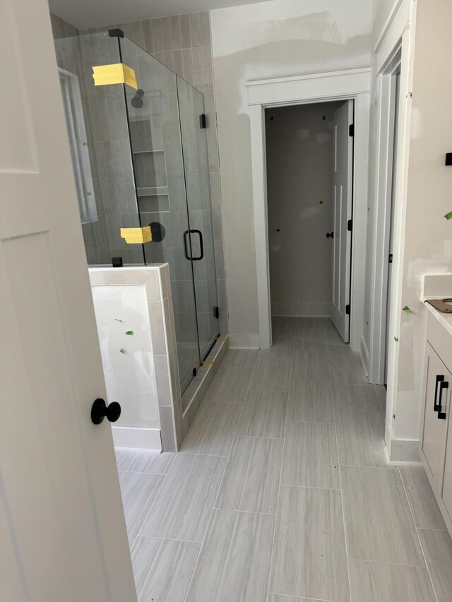 full bathroom featuring a stall shower, vanity, and baseboards