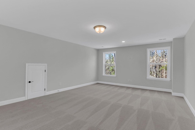 unfurnished room with light carpet, visible vents, and baseboards