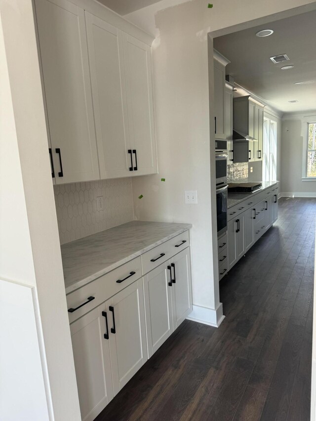 kitchen featuring black electric stovetop, dark wood-type flooring, visible vents, and baseboards