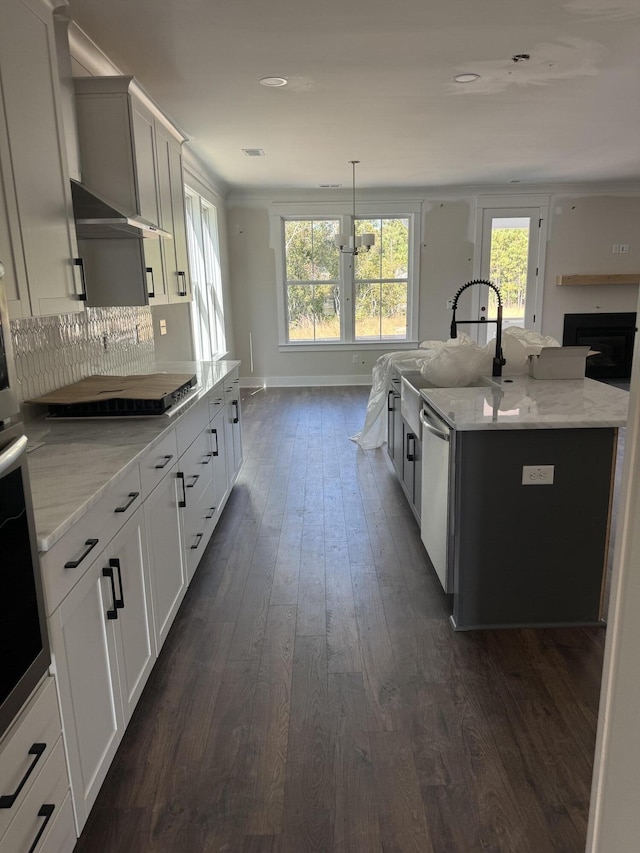 kitchen featuring a sink, appliances with stainless steel finishes, dark wood-type flooring, and light stone counters