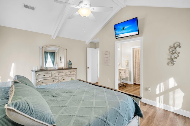 bedroom featuring ceiling fan, connected bathroom, light hardwood / wood-style flooring, and lofted ceiling with beams