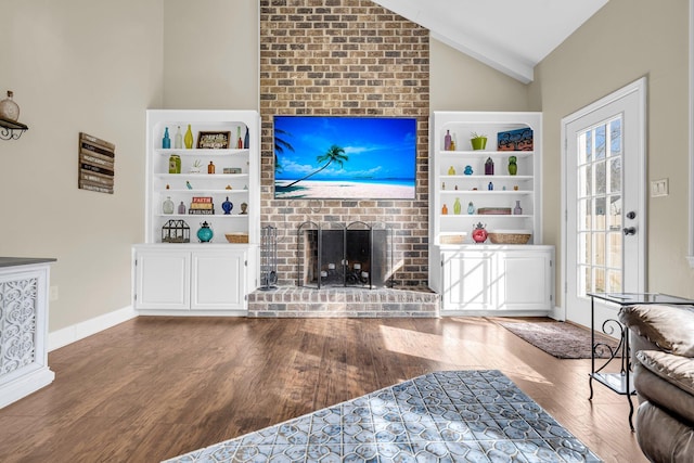 living room with vaulted ceiling, a brick fireplace, a healthy amount of sunlight, and wood-type flooring